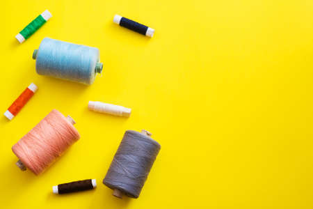 Reels with threads of different colors and sizes on a bright, colorful background. Flat lay. Place...