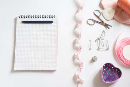 Sewing materials - a box with threads of bright colors, a pink ribbon, cotton, measuring tape on a...