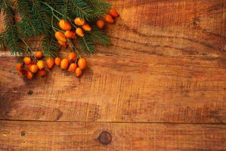 Winter, warm atmosphere. Frame with red scarf, rose berries and spruce on wooden background. Winter evening. Flat lay, layout, place for text, post card, high resolutionの写真素材