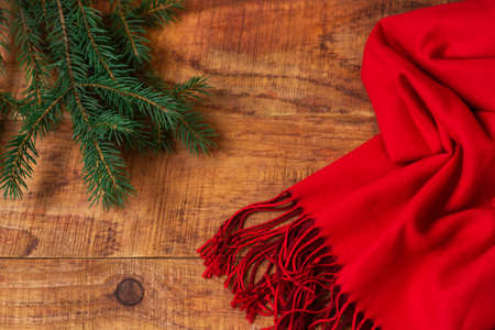 Winter, warm atmosphere. Frame with red scarf and spruce on wooden background. Winter evening. Flat lay, layout, place for text, post card, high resolutionの写真素材