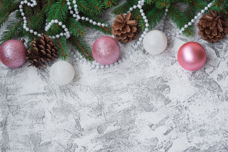 New Years or Christmas composition of spruce green branches decorated with beads, pine cones and New Years, shiny toys on a bright textural background. Flat lay, layout, frame, copy spaceの写真素材