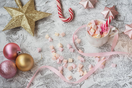 New Years or Christmas composition cup with marshmelow with candy among New Years, shiny toys and golden star on a bright textural background. Flat lay, layoutの写真素材