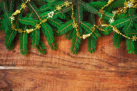 Christmas background. Spruce branches and golden garland on a wooden background. Copy space, frame, place for text. Top view. Christmas or New Years card. flat layの写真素材