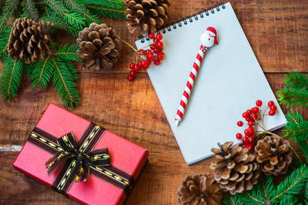 Christmas background. Spruce branches, red berries, notebook, gift, and cup with marshmallows on a...