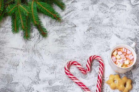 New Year's or Christmas composition of spruce green branches, New Year's lollipops, cup with marshmallows and cookies on a bright textural background. Flat lay, layout, copy spaceの写真素材