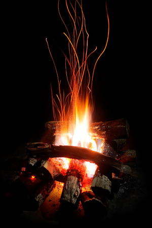 Flames and sparks of a wood camp fire at night focus on flameの写真素材