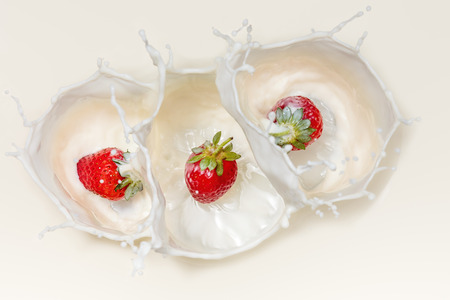 Three Fresh Red Strawberries splashing in white milk from from aboveの写真素材