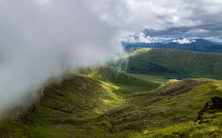 Dramatic summer Scottish Highlands landscape. Low clouds rolling over mountain ridge of Beinn...