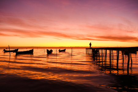 boats at sunrise on the shore of the lakeの写真素材