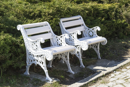 Tiny white benches in a park made of forged ironの写真素材