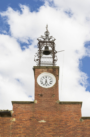 Brick church tower with clock and bell attached to an iron frameの写真素材