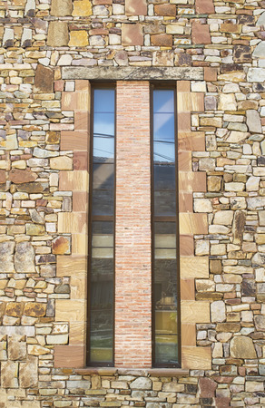 Long , vertical windows separated by a layer of decorative bricks on a stone plated wallの写真素材