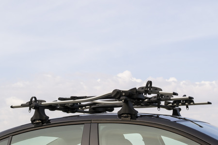 Bicycle carrier system mounted on the roof of a car against a blue sky backgroundの写真素材