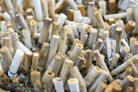 Cluster of cigarette butts gathered from various smokers in an ashtrayの写真素材