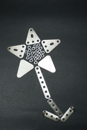 Perforated metallic pieces arranged to form a metallic flower against a black backgroundの写真素材