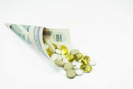 Different pills inside a banknote wrapped in a cone shape, conceptual image about the cost of health care , isolated on whiteの写真素材