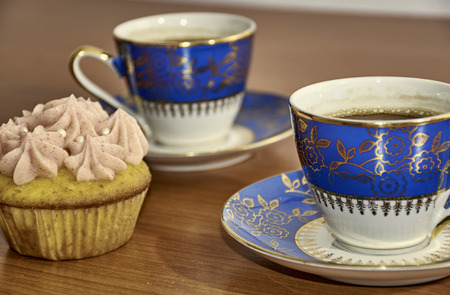 Delicious dessert with rosewater flavoured cupcake and two porcelain coffee cupsの写真素材