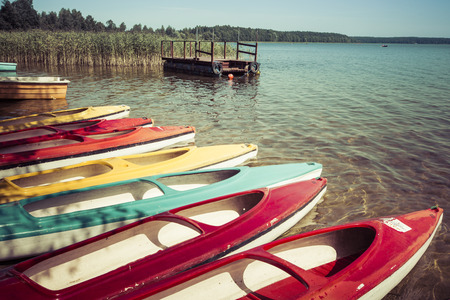 Colorful kayaks moored on lakeshore, Goldopiwo Lake, Mazury, Poland.の写真素材