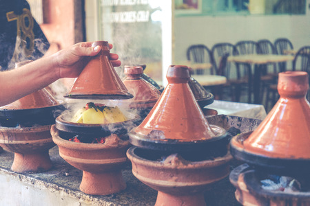 Preparing food in tajin traditional dish in Morocco - meat and vegetable in a ceramic tajine.