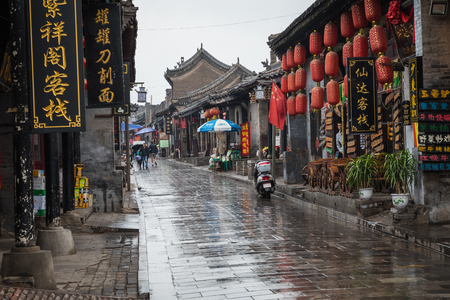 PINGYAO, CHINA - MAY 21, 2018: Tourists and local people in the ancient city of Pingyao in central China, Asia. Rainy weather.のeditorial素材
