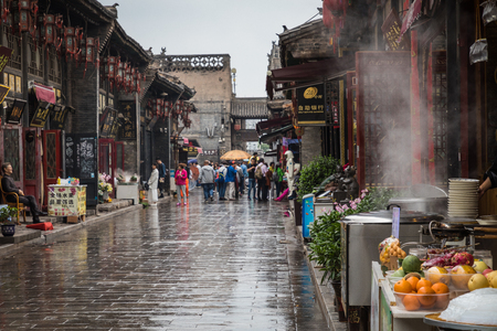 PINGYAO, CHINA - MAY 21, 2018: Tourists and local people in the ancient city of Pingyao in central China, Asia. Rainy weather.のeditorial素材