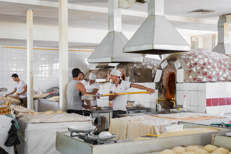 TASHKENT, UZBEKISTAN - AUGUST 22, 2018: Uzbek people baking traditional uzbekistan bread.