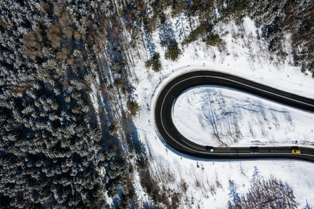 Curvy windy road in snow covered forest, top down aerial view. Winter landscape.の写真素材