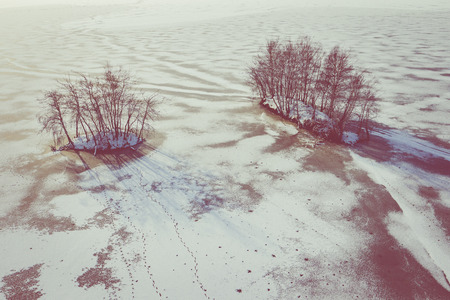 Aerial view of the winter snow covered forest and frozen lake from above captured with a drone.