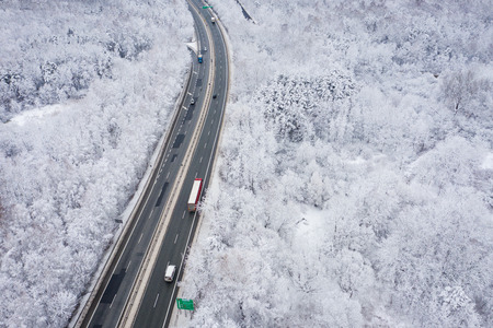 Aerial view of winter beautiful landscape road with trees covered with hoarfrost and snow.  Winter scenery from above. Landscape photo captured with drone.の写真素材