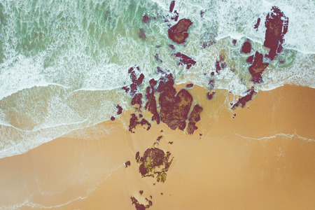 Aerial view to ocean waves. Yellow sand beach. Blue water background. Photo made from above by...