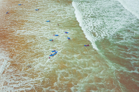 Aerial view sufrers in the ocean waves. Blue water background. Photo made from above by drone.