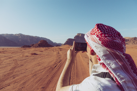 A tourist standing by the look out of a panoramic view of the desert in Wadi Rum, Jordan, Middle East.の写真素材