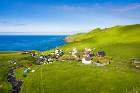 Aerial view of village at Mykines island in Faroe Islands, North Atlantic Ocean. Photo made by drone from above. Nordic natural landscape.の写真素材