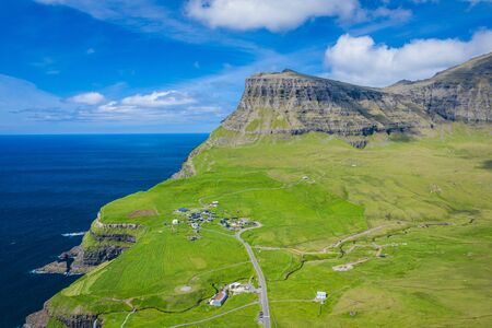 Aerial view of Mulafossur waterfall in Gasadalur village in Faroe Islands, North Atlantic Ocean. Photo made by drone from above. Nordic Natural Landscape.の写真素材