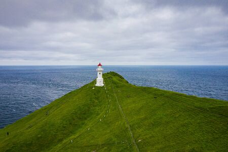 Aerial view of lighthouse at Mykines island in Faroe Islands, North Atlantic Ocean. Photo made by drone from above. Nordic natural landscape.の写真素材