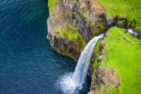 Aerial view of Mulafossur waterfall in Gasadalur village in Faroe Islands, North Atlantic Ocean. Photo made by drone from above. Nordic Natural Landscape.の写真素材
