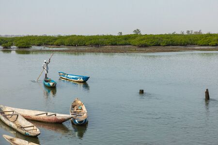 JOAL-FADIOUTH, SENEGAL - NOVEMBER15, 2019: Fishers and small long boats. Fadiauth Island. Senegal....
