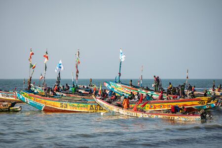 TANJI, THE GAMBIA - NOVEMBER 21, 2019: Scene with men and women carrying fish from the boats to the...