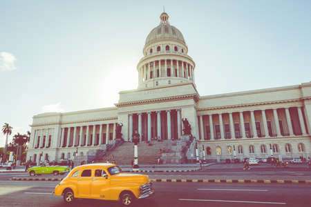 HAVANA, CUBA - DECEMBER 10, 2019: Brightly colored classic American cars serving as taxis pass on the main street in front of the Capitolio building in Central Havana, Cuba.のeditorial素材