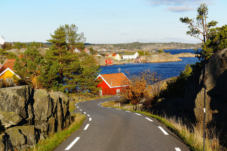 Asphalt road to the harbor with views of the rocky coast, among the rocks, among the bushes. Blue...