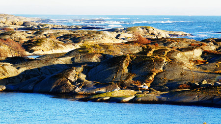 Waves in the sea, along the flat rocky coast. North Sea Coast. Norwegian winter. The sun low on the horizon. Telemark region of Norwayの写真素材