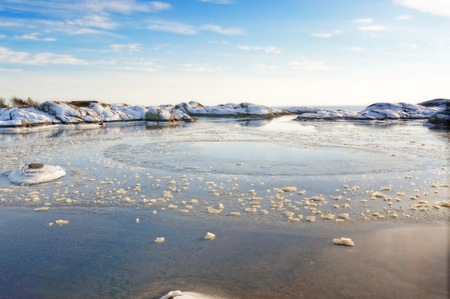 Water outlet from the bay to the sea, at the center of a circular trace of the boat. A sea tide at bay fjord visible in winter. Bay fjord covered in ice in the winter. Wavy rocks covered with snow.. In the background of the North Sea. Visible signs of outのeditorial素材