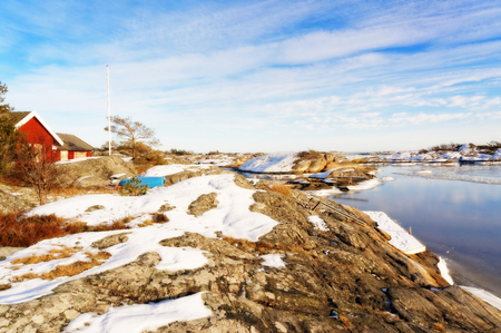 View from the coast on a small island shelf, islets covered with snow. Around a small bay. Rocks covered with snow in January. Visible signs of outflow of the sea. Blue sky. Winter in Aust-Agder municipality. Region of southeastern Norway. North Sea Coastのeditorial素材