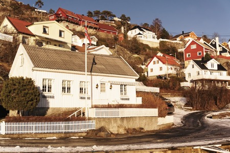Kragero, Telemark. Norway - February 2015. Summer holiday homes on the hill. Snow on the roof. Snow on bushes and trees. Asphalt road among the houses.のeditorial素材