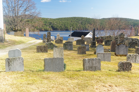 Drangedal, Norway, March 21, 2015: Cemetry situated by lake Tokevann. Square tower surrounded by graves with similar headstones and between them manicured lawn. Early spring.のeditorial素材