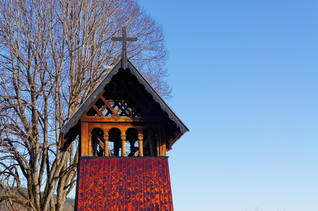 Heddal, Norway, March 21, 2015: Old traditional temple bell tower of the temple wooden sloping roof of the old temple, a small cross on roof. Early spring.の写真素材