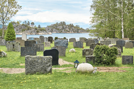 OSPEVIKA, NORWAY - May 25, 2015Norwegian cemetery early spring. Old crosses covered with rust. Granite plates. Around the rocks. A view of the fjord. The cemetery opened in 1865. Region Norway - Telemark, village Kragero.のeditorial素材