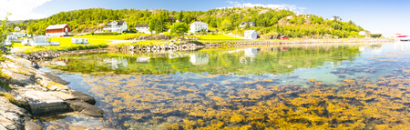 Kongensvoll Hitra, Norway - August 19, 2016:  Beach and shallow bay of Norwegian fjord. Brown algae. Greenish water. A view of the salmon farm.のeditorial素材