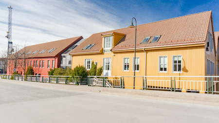 Kristiansand, Norway - June 4, 2015: Norwegian asphalt street. Colorful industrial wood buildings. Bay in Kristiansand.のeditorial素材