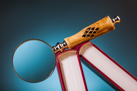 books on wooden table and magnifying glass  with blue backgroundの写真素材